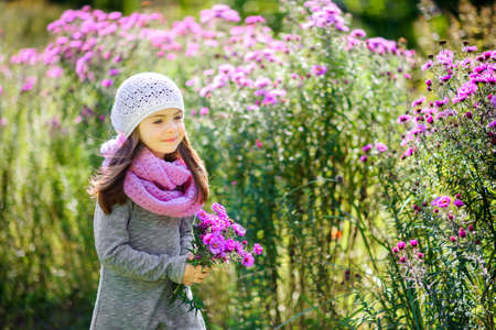 happy little girl is walking in a beautiful park with a bouquet of flowersの写真素材
