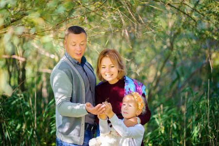 happy family walks in the evening park, dad catches a butterfly and shows his daughter