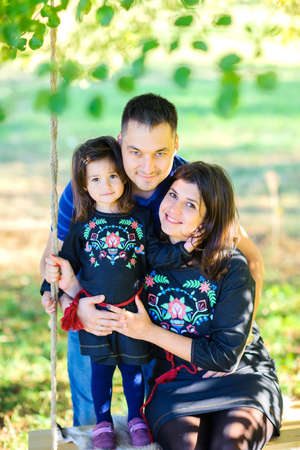 happy family riding on a swing in the evening parkの写真素材