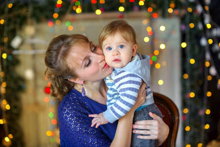 happy mother with her beloved baby, holds on her hands and gently kisses, against a background of...