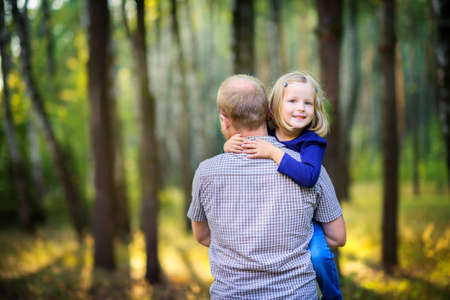 dad walks in the park with his beloved daughter at sunset, holds and hugsの写真素材