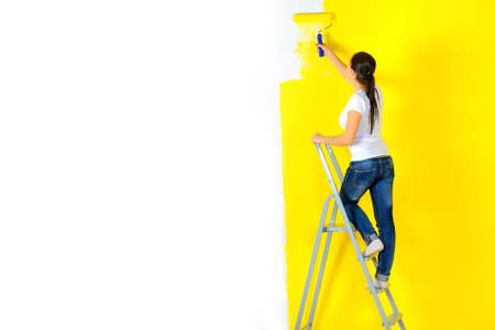 girl painter paints a wall with a platen standing on a staircaseの写真素材