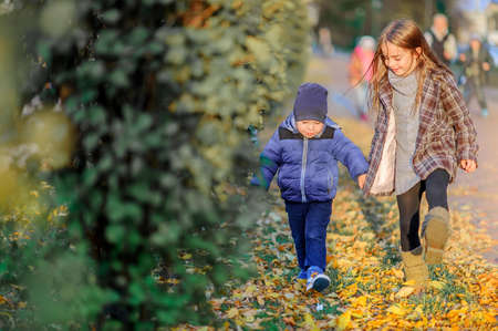 boy and girl walk on the fallen leaves holding hands