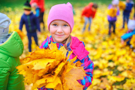 smiling girl with a bouquet of intense autumn leavesの写真素材