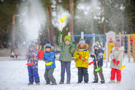 cheerful children play in a winter park, throw snow and have funの写真素材