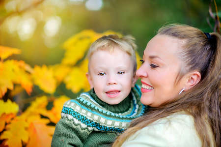 happy mother with her little son goulabt in autumn park at sunsetの写真素材