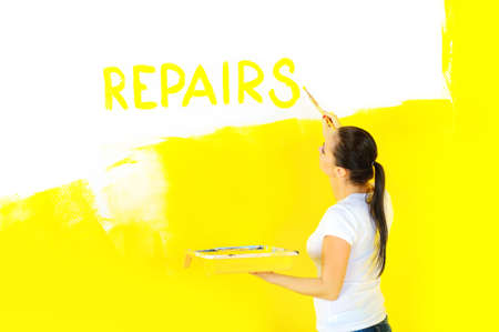 woman painter holding a bathtub with paint and writing a brush on the wall of the word repair