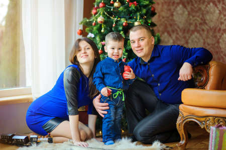 happy family sitting on the floor near the festive Christmas tree and enjoying the gifts