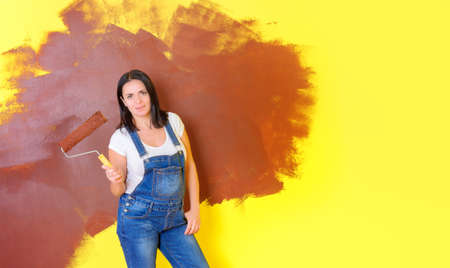 female house painter with a paint roller, the beginning of the repair in the house