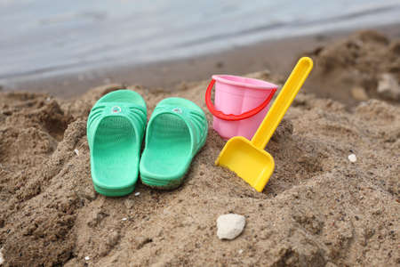 Closeup of children slippers and toys on beachの写真素材