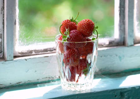 Glass of strawberries on window-sillの写真素材