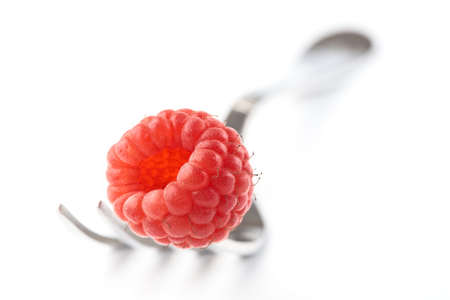 Raspberry on fork isolated on white background