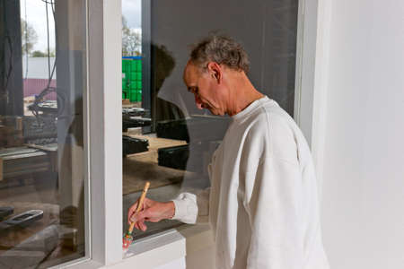 Painter on the job. Painting the inside of a new factory building with an officeの写真素材