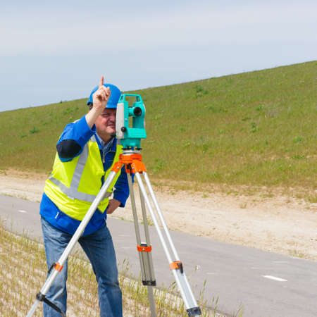 Engineer working with a modern theodolite or total station on a tripod の写真素材