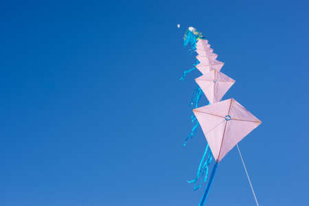 Multiple kites on a row against a blue skyの写真素材