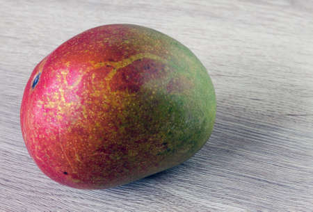 close up of a mango fruit on an oak table surface with a faint backgroundの写真素材