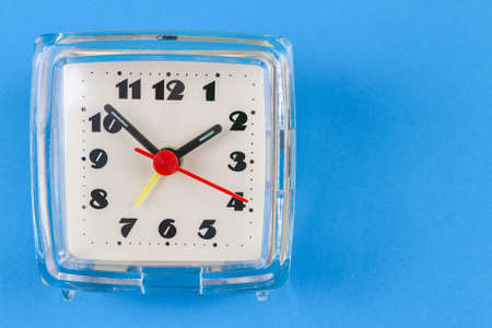 old table quartz clock in a plastic case on a blue background with space for a copyの写真素材