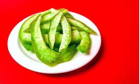 lots of candied grapefruit peel slices on a plate on a red backgroundの写真素材