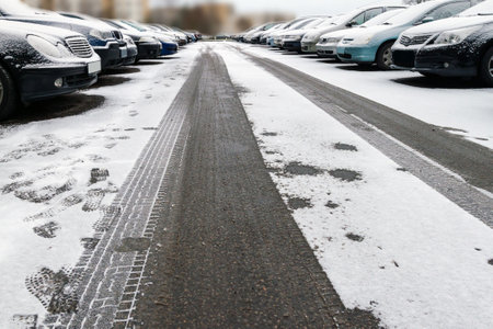 snow-covered cars standing in the yard in the winter with ruts and tracesの写真素材