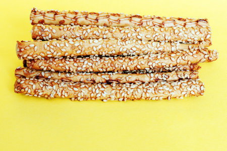 a large bunch of sticks with sesame seeds on a yellow background with space for text