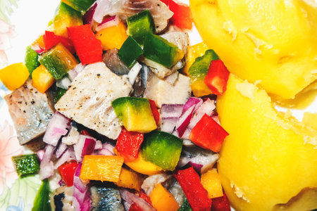 Herring with tricolor peppers, onion with oil and potatoes on a plate, top view, macroの写真素材