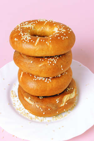 Steamed and fried rolls with a hole in a white plate arranged vertically on a pink background