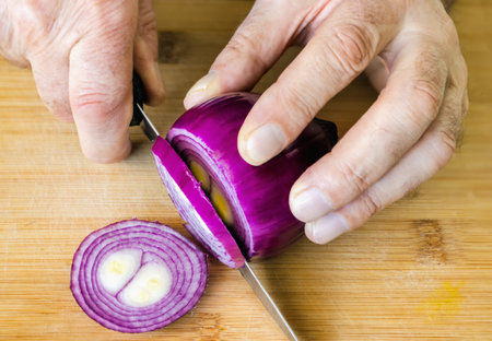 Cut the red onion into slices with a knife on a cutting boardの写真素材