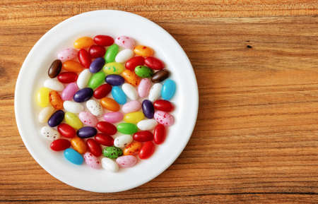 Candy jelly beans assorted in a plate on a pine tree surface, top viewの写真素材