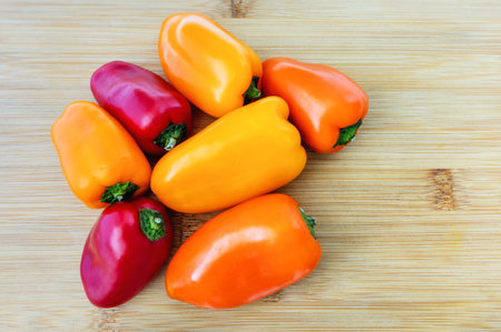 A bunch of small sweet peppers on a bamboo cutting board, view from aboveの写真素材