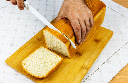 Sliced white bread loaf from Lithuania with a ceramic toothed knife on a cutting board