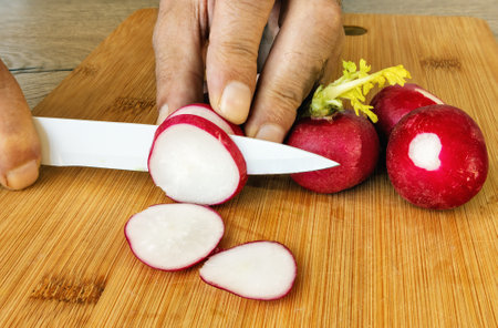 Male hands with a ceramic knife cut radishes on a cutting board
