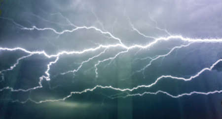 Bright lightning in the black sky through the frosted window glass