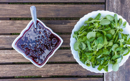 Cranberry jam bowl for sauce and bowl with beet leaves for salad on a wooden outdoor table