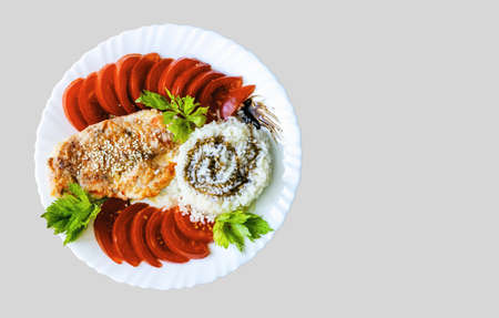 Fried chicken breast with tomatoes, parsley, rice and balsamic sauce on a plate on a gray background