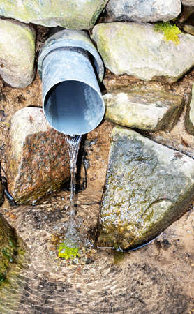 Summer between the rocks water running from the drainage pipeの写真素材