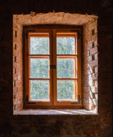 Old wooden window in a thick red brick wall, view from the inside