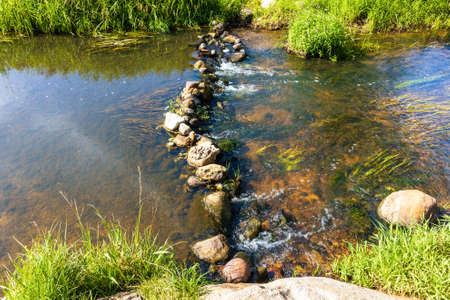 A stream of water splashing in the summer through a cascade of rocks