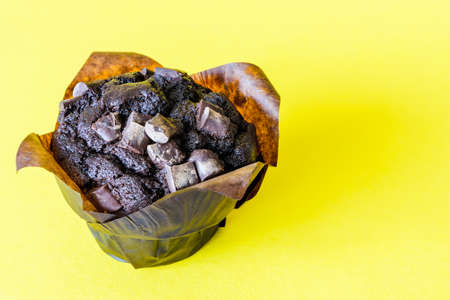 Chocolate cake with pieces of chocolate with baking paper on a yellow background with space for textの写真素材