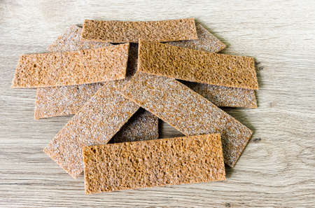 Bread chips with sesame, coriander, pumpkin, sunflower on the surface of an ash tree table