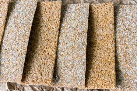 Thin bread chips with sesame, coriander, pumpkin, sunflower seeds on food paper