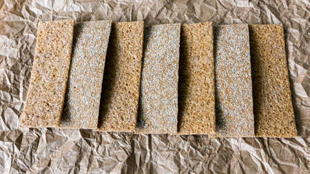 Bread chips with sesame, coriander, pumpkin seeds on crumpled food paper