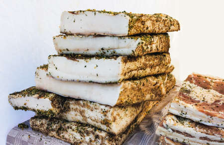 A bunch of pieces of smoked bacon on a tablecloth outside in a market tentの写真素材