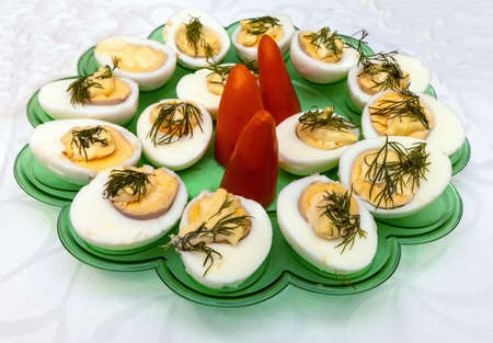 Boiled eggs with paprika and dill in a green tray on a tableclothの写真素材