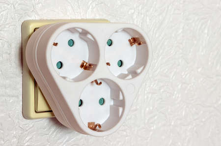 White three-pronged socket adapter with grounding in the room wall front viewの写真素材