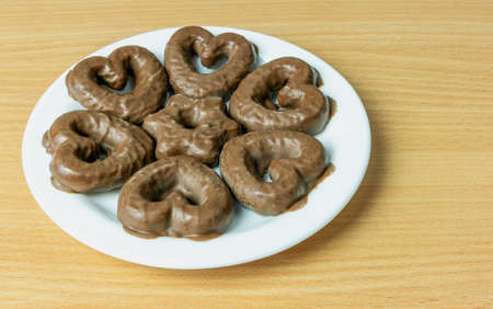Side view of milk chocolate covered heart shaped cookies on a plate on a table surfaceの写真素材