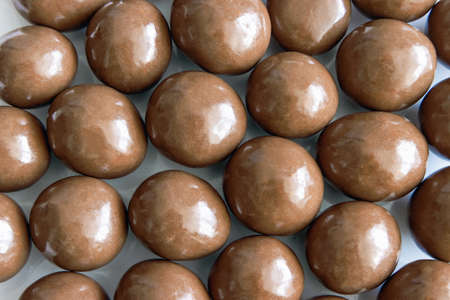 Hazelnuts are sprinkled on a plate surface covered with milk chocolate