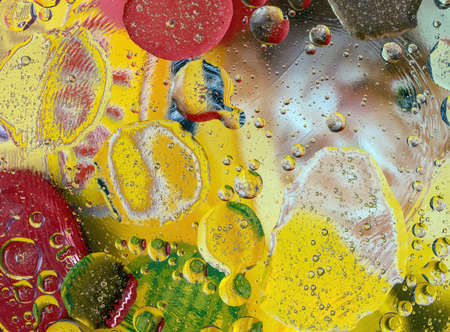 Background of colored droplets of oil and water with reflections of light and color