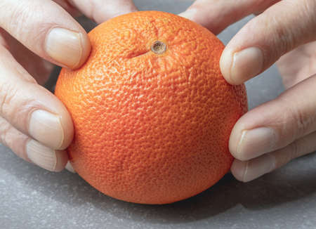 Grapefruit ripe fruit in hands on a ceramic surface against a blurred backgroundの写真素材