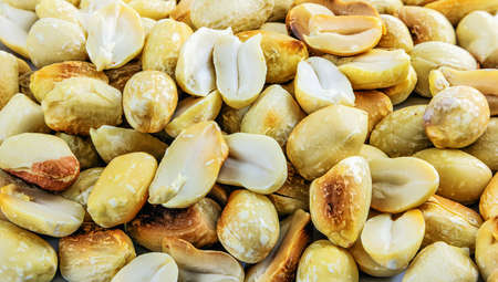 Pile of close-up roasted and peeled peanuts in the background, top view