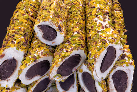 Nuga with chocolate-filled pistachio seeds on a black background up close